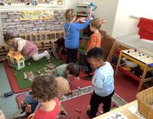 An image of children playing with cars and a doll's house.
